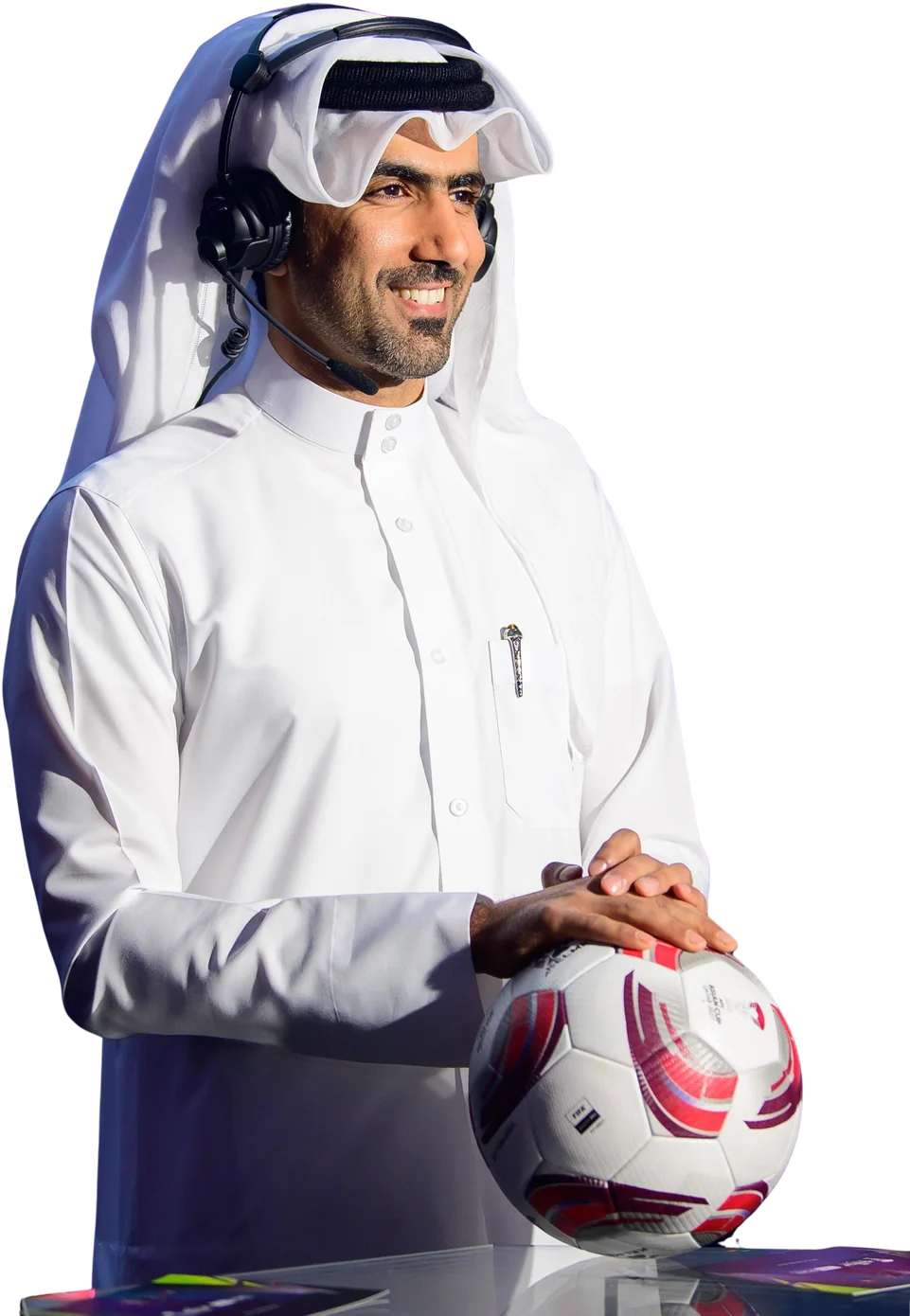 Mohammed Saadon Al Kuwari in traditional Qatari dress with a football and broadcast headset